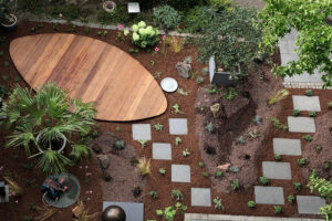 fertige Gartenbepflanzung, frisch abgemulcht und mit Wegführung durch Trittplatten zu der neuen ovalen Holzterrasse aus der Vogelperspektive