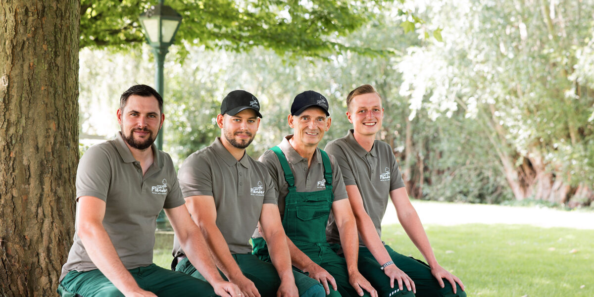 Das Team sitzt nebeneinander im Garten